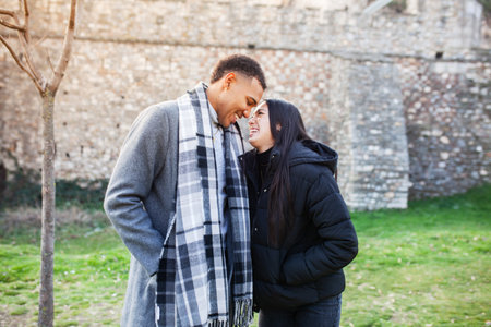 Man and woman posing in front of an old stone wall. Multiracial couple in love.の写真素材