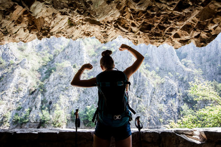 Silhouette of a young and happy hiker girl standing in a rocky passageの写真素材