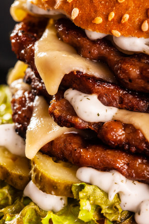 Abstract junk food. Quadruple burger with cheese cucumber and lettuce. Fast food background texture.の写真素材
