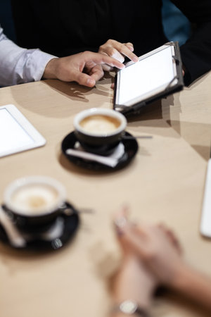 Colleagues having a business meeting at a cafe. Drinking coffee and working on laptop and tablet.の写真素材