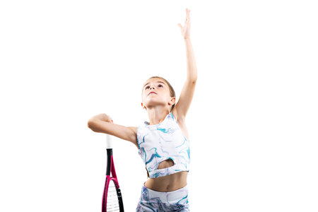 Young female tennis player. Little girl posing with racket and ball isolated on white background.