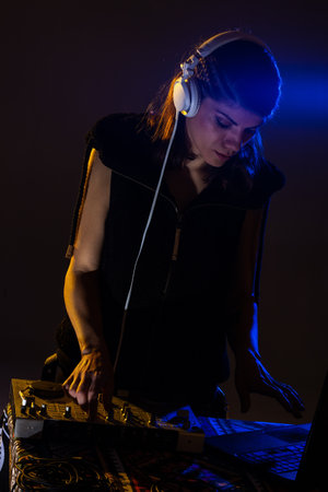 Female DJ playing music on a mixer. Blue light flare visibleの写真素材
