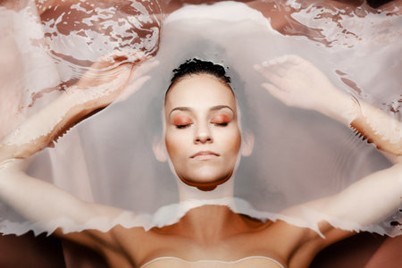 Underwater beauty portrait of a beautiful caucasian girl. Eyes closed. Red colored water.