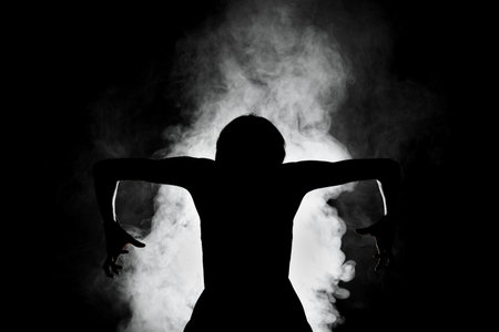 silhouette modern ballet dancer posing on dark background with smokeの写真素材