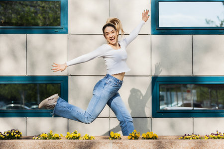 Beautiful girl jumping infront of modern building facade.の写真素材