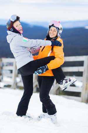 Two beautiful ski girls posing outdoors. Skier friends having fun.の写真素材