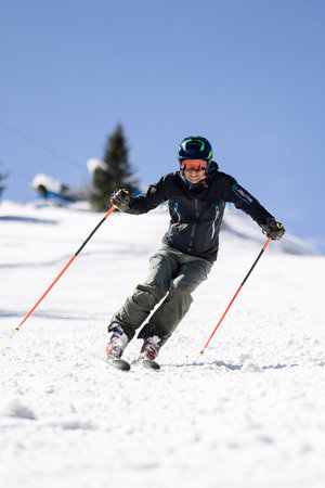 Professional skier skiing on slopes in a mountain winter resort. Sunny day with clear sky.の写真素材