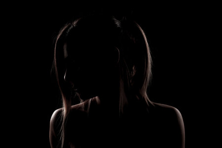 Beautiful caucasian girl posing yoga in shadow. side lit photo on black background.
