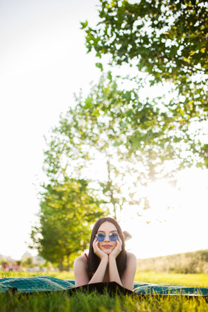 Beutiful dark hair girl with sunglasses lying on a meadow in the park.の写真素材