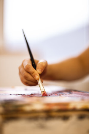 Hand using brush on an artistic painting. Female artist creating art.の写真素材