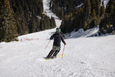 Professional skier skiing on slopes in a mountain winter resort. Sunny day with clear sky.