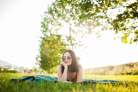 Beutiful dark hair girl with sunglasses lying on a meadow in the park.の写真素材