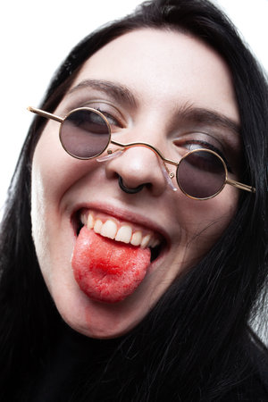 Gothic girl with white eyes and bloody mouth smiling with tongue out.