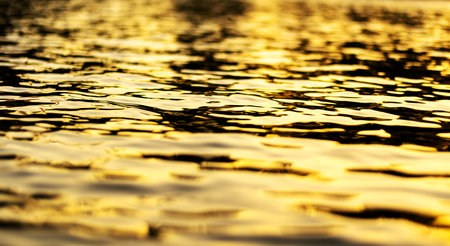 Golden sunset reflections on a tranquil rippling water surfaceの写真素材