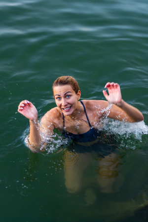 Joyful woman swimming in refreshing lake on a sunny dayの写真素材