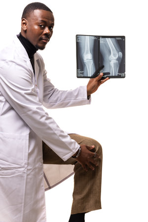 A medical professional examines x-ray of knee joint, showcasing medical expertise and care in diagnosing and treating musculoskeletal conditions, wearing a white lab coat in a professional environment.の写真素材