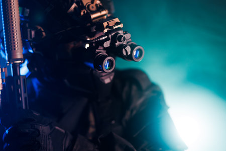A figure in tactical gear uses night vision equipment, captured in dramatic green and blue lighting.の写真素材