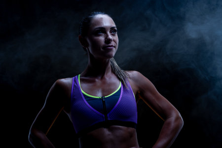 A determined woman wearing a sporty outfit stands in a smoky ambiance, embodying strength and fitness focus, showcasing her inspiring and empowering athletic presence.の写真素材