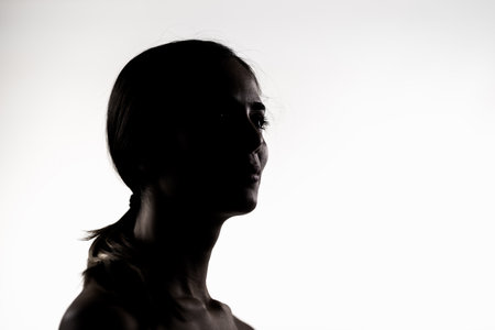 Silhouette of a young woman in a studio setting, low key lighting portraitの写真素材