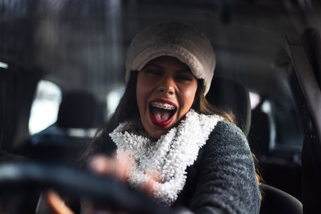 Excited Young Woman Smiling While Driving and Enjoying an Energetic Winter Day