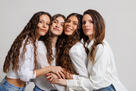 Group of Four Women Embracing in a Studio Setting in Coordinated Outfitsの写真素材
