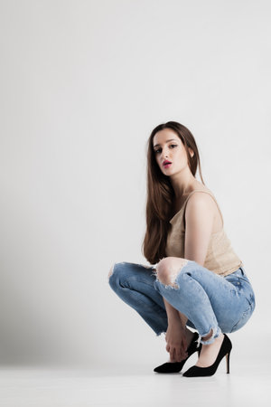 Young woman in casual attire posing in a studio against a white background