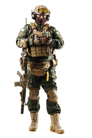 Tactical Soldier in Full Gear Conducting Communication on Deviceの写真素材