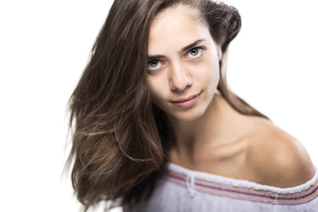 Close-up portrait of a young woman with flowing hair and natural makeup in a studio settingの写真素材