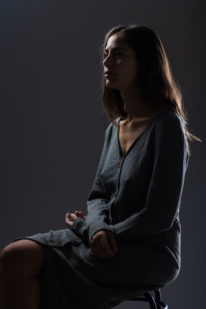 Elegant young woman in grey dress posing in studio with dramatic lightingの写真素材