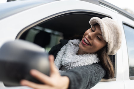 Young woman smiling and capturing a selfie through the car window on an outdoor adventureの写真素材