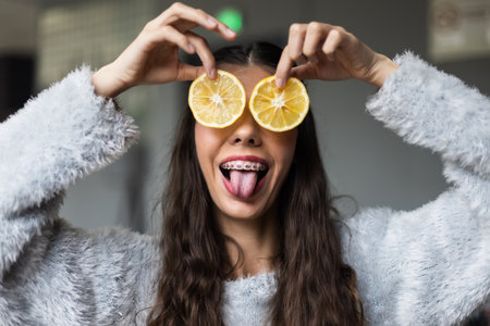 Joyful Young Woman Holding Lemon Slices in a Fun and Creative Poseの写真素材