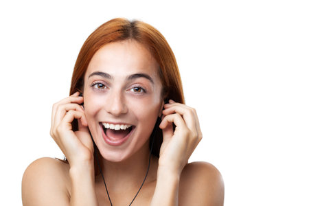 Portrait of a joyful young woman with auburn hair, smiling broadly while talking, isolated on a...