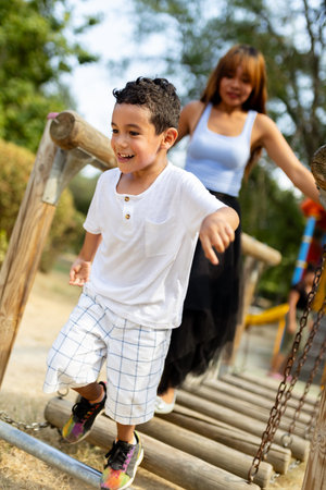 Boy Having Fun on a Play Structure in the Park With Family in the Backgroundの写真素材