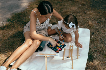 Mother and daughter painting in an outdoor setting on a sunny dayの写真素材