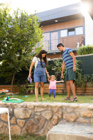 Family enjoying quality time outdoors with their young child in a sunny backyard