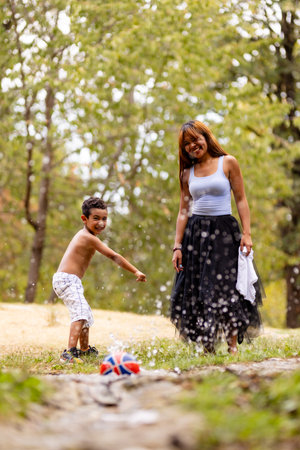 Mother and son enjoying a playful moment outdoors with splashing waterの写真素材