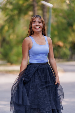 Smiling Woman in Stylish Tulle Skirt and Tank Top Enjoying a Sunny Day Outdoorsの写真素材