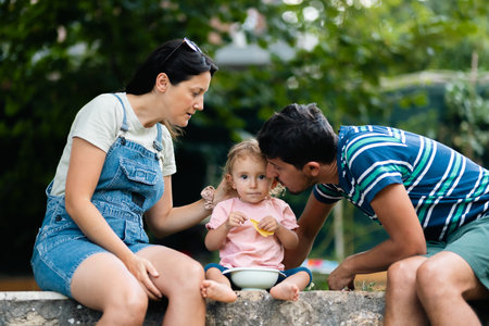 Parents spending quality time outdoors with their daughter in a warm day.の写真素材
