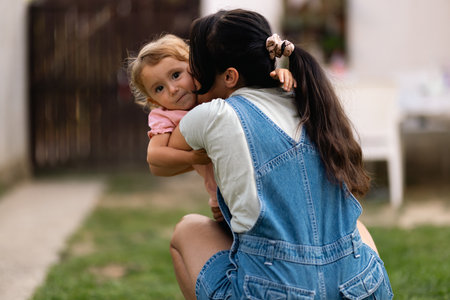 Mother Embracing Her Child Outdoors During a Warm, Sunny Dayの写真素材