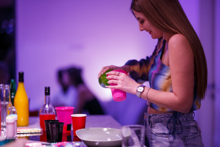 Young woman preparing drinks at a colorful party with vibrant lighting