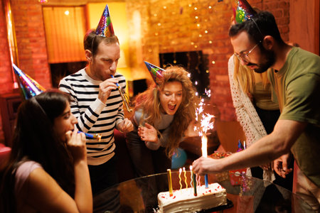 Group of friends celebrating birthday with cake and party decorations in a cozy indoor setting