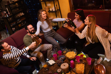 Group of friends spending a joyful evening gathering with laughter and drinks in a casual home...