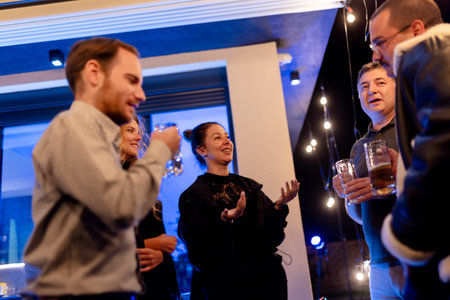 Group of friends enjoying drinks and conversation at an outdoor evening gatheringの写真素材