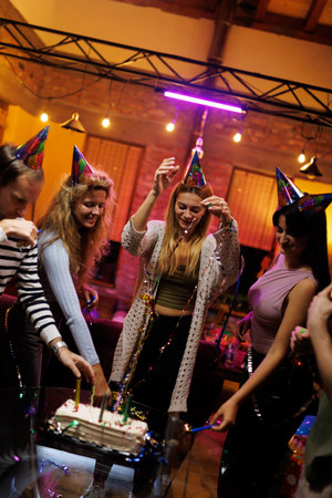 Group of friends celebrating with hats, cake, and decorations indoors