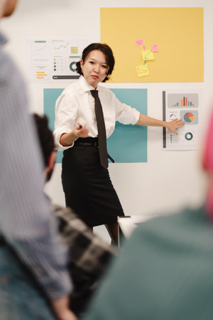 Business meeting in a modern workspace with a woman presenting data to colleagues during a team...