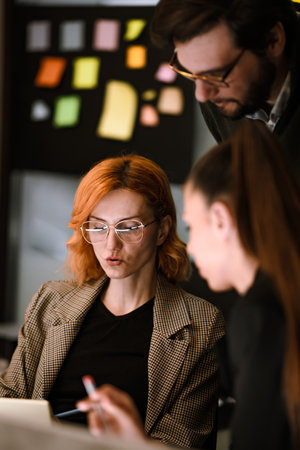 Creative brainstorming session with colleagues discussing ideas in a modern office setting during evening hoursの写真素材