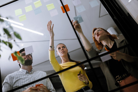 Group collaboration on project planning with sticky notes in a modern office setting during a brainstorming sessionの写真素材