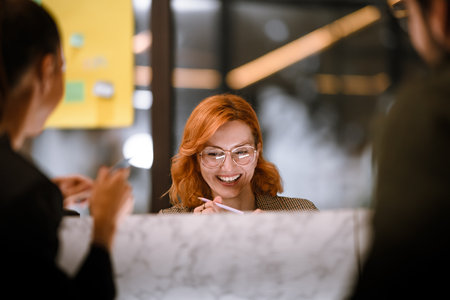 Smiling woman with glasses enjoying a conversation with friends at a modern cafe during an afternoon gatheringの写真素材