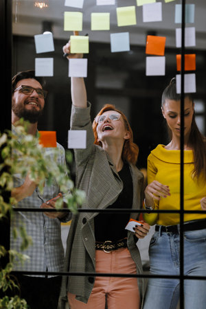 Team brainstorm session with colorful sticky notes at a creative workspace, showcasing collaboration and idea generation during a bright afternoonの写真素材