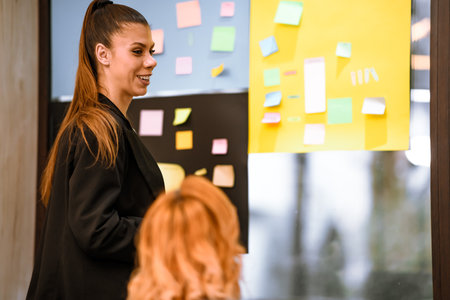 Engaging team discussion in a modern workspace with sticky notes on the wallの写真素材